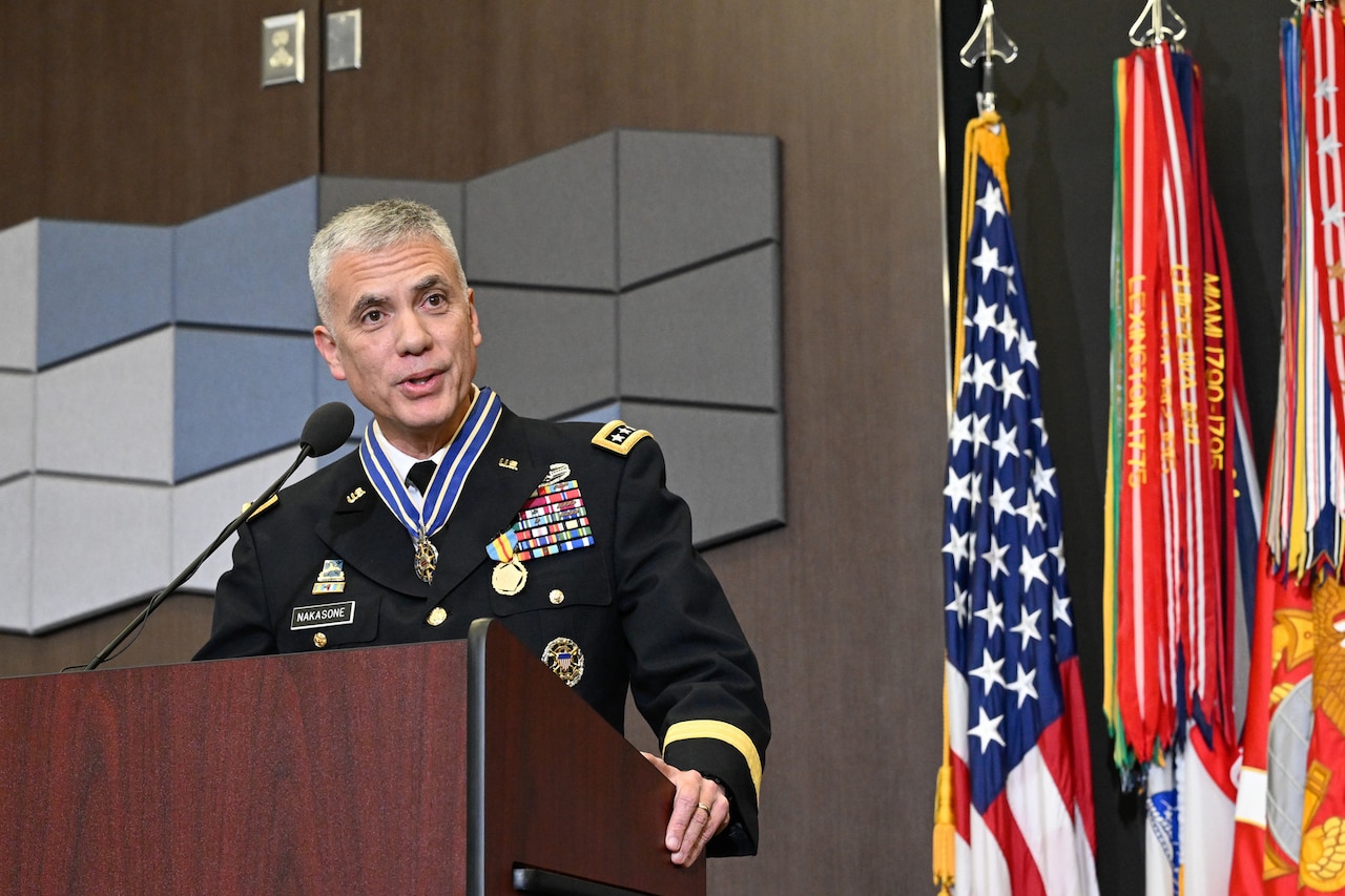 A man speaks from a podium as others watch.