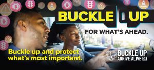 Father and son driving in a car. Text that says: Buckle up for what's ahead. Buckle up and protect what's most important. Arrive Alive DE