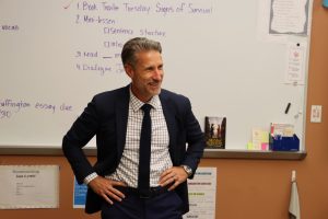 Secretary of Education Mark Holodick stands in front of a classroom smiling.